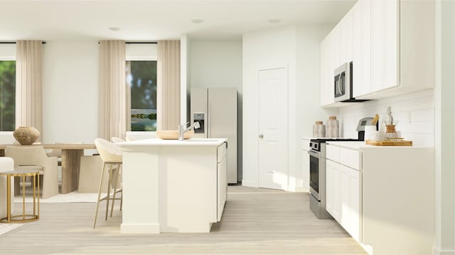 kitchen featuring white cabinets, stainless steel appliances, backsplash, a kitchen island with sink, and a breakfast bar