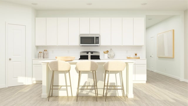 kitchen featuring white cabinetry, range, tasteful backsplash, and a kitchen island with sink