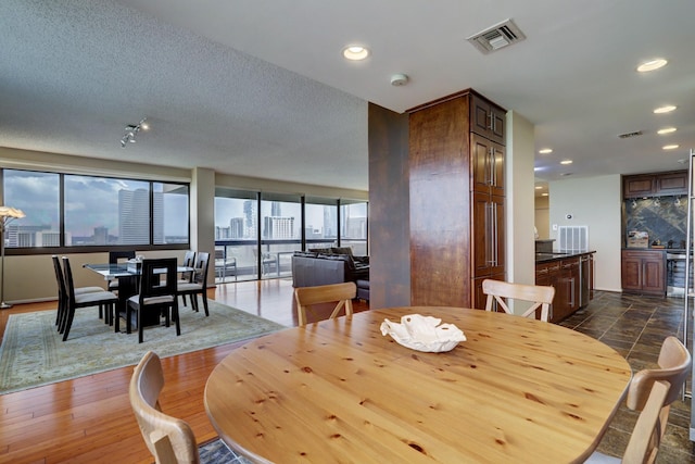 dining space with a textured ceiling, dark hardwood / wood-style flooring, and a healthy amount of sunlight