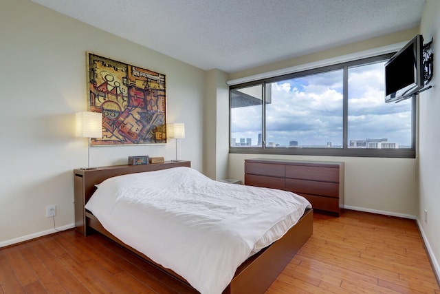 bedroom with light wood-type flooring and a textured ceiling