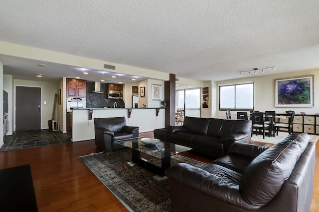 living room featuring rail lighting, dark wood-type flooring, and a textured ceiling