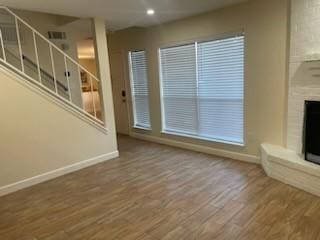 unfurnished living room with wood-type flooring and a large fireplace