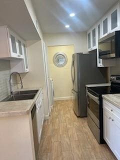 kitchen with light wood-type flooring, white cabinetry, black range with electric stovetop, and sink