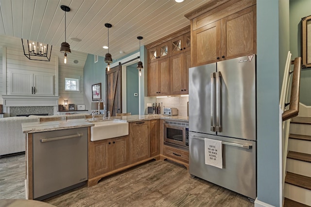 26210 Bluejack National Blvd Unit 14, Montgomery, TX 77316 - kitchen featuring sink, a barn door, light stone counters, wood ceiling, and stainless steel appliances