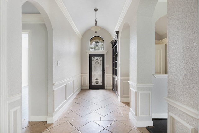 entryway featuring light tile patterned flooring, vaulted ceiling, and ornamental molding