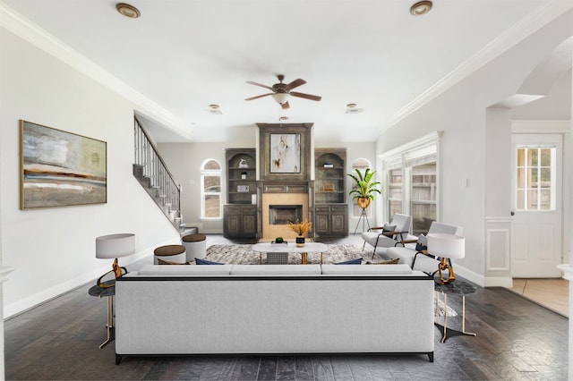 living room featuring ceiling fan, a fireplace, ornamental molding, and dark wood-type flooring