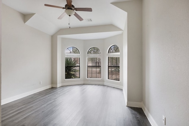 empty room with dark hardwood / wood-style floors, vaulted ceiling, and ceiling fan