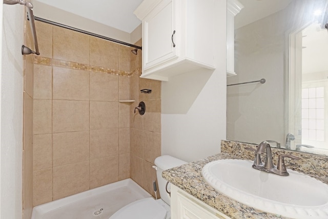 bathroom featuring vanity, toilet, and a tile shower