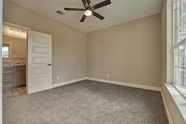 unfurnished bedroom with ceiling fan, ensuite bathroom, and light carpet