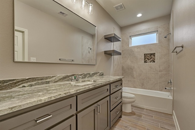 full bathroom with vanity, tiled shower / bath combo, and toilet