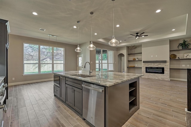 kitchen with stainless steel appliances, ceiling fan, sink, decorative light fixtures, and an island with sink