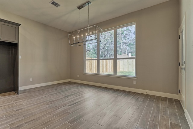 unfurnished dining area with light hardwood / wood-style floors and an inviting chandelier