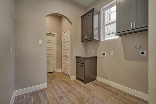 3050 Willowbend Rd, Montgomery, TX 77356 - laundry room featuring hookup for an electric dryer, cabinet space, light wood-style flooring, washer hookup, and arched walkways