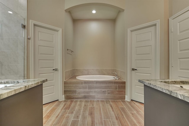 bathroom featuring vanity and tiled tub