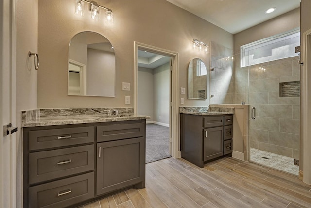 3050 Willowbend Rd, Montgomery, TX 77356 - bathroom with a shower stall, wood finished floors, and two vanities
