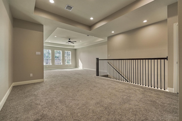 spare room featuring a tray ceiling, ceiling fan, and carpet floors