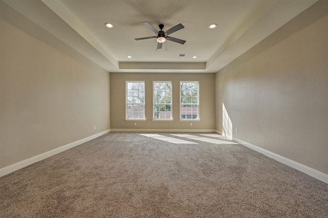 carpeted empty room with ceiling fan and a tray ceiling