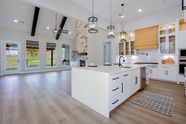 kitchen with high vaulted ceiling, sink, ceiling fan, an island with sink, and beam ceiling