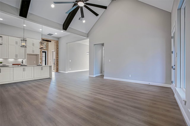 unfurnished living room featuring beam ceiling, ceiling fan, high vaulted ceiling, and light hardwood / wood-style floors