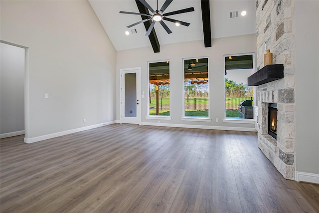 unfurnished living room featuring beam ceiling, ceiling fan, a stone fireplace, high vaulted ceiling, and hardwood / wood-style flooring