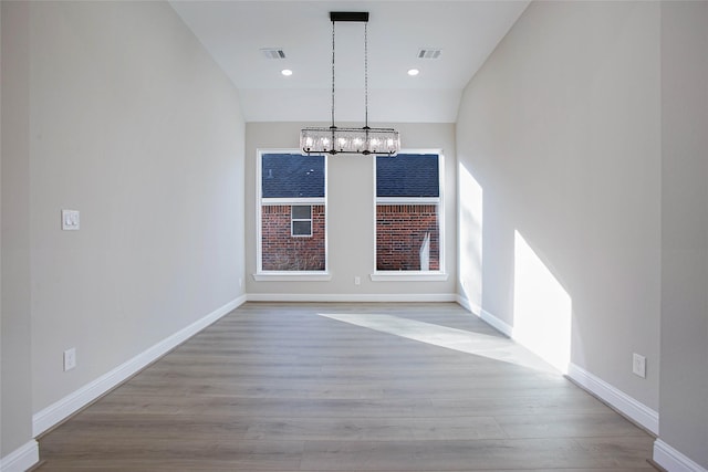 unfurnished dining area with a chandelier and light wood-type flooring