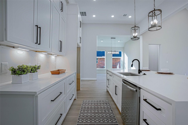 kitchen featuring white cabinets, sink, pendant lighting, dishwasher, and an island with sink