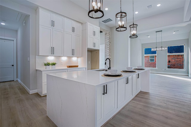 kitchen with white cabinetry, sink, an island with sink, and pendant lighting