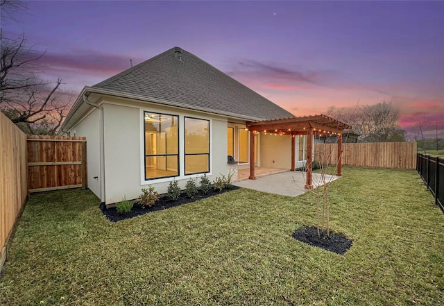 back house at dusk with a lawn, a pergola, and a patio