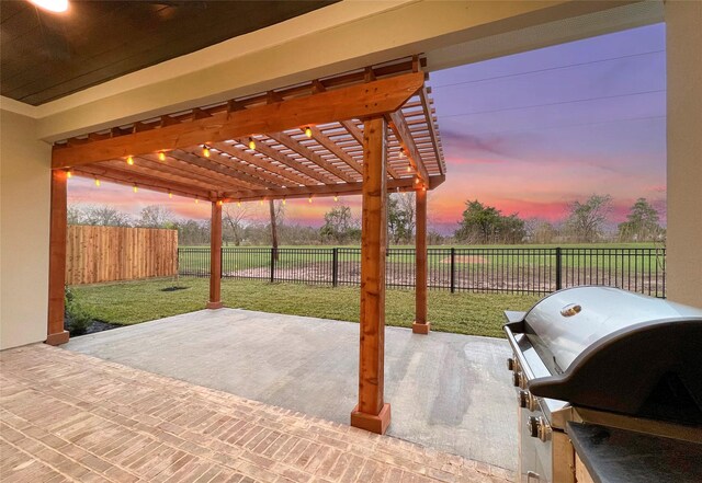 patio terrace at dusk with a pergola, grilling area, and a lawn