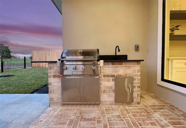 patio terrace at dusk with grilling area and an outdoor kitchen