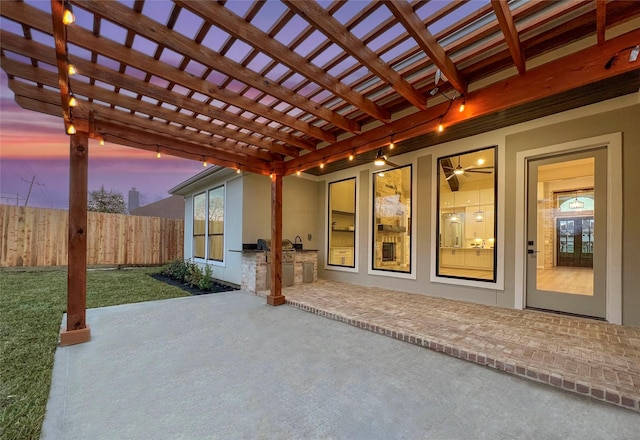 patio terrace at dusk with a pergola and area for grilling