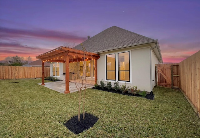 back house at dusk featuring a yard, a pergola, and a patio