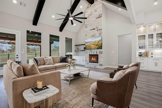 living room with beam ceiling, light hardwood / wood-style floors, high vaulted ceiling, and ceiling fan