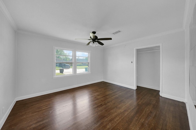 empty room featuring ceiling fan, crown molding, and dark wood-type flooring