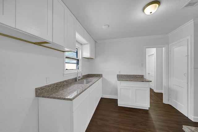 kitchen with dark hardwood / wood-style flooring, white cabinetry, sink, and ornamental molding