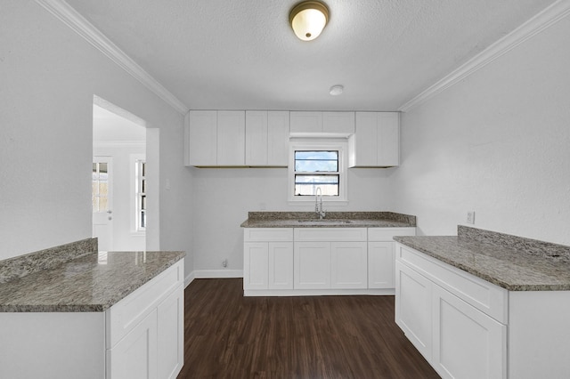 kitchen with dark stone counters, ornamental molding, sink, dark hardwood / wood-style floors, and white cabinetry