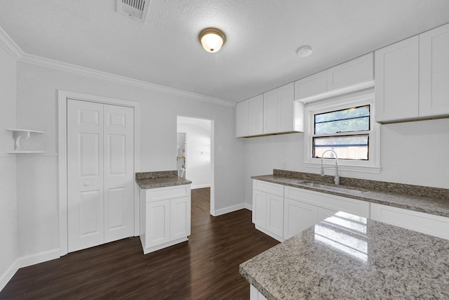 kitchen featuring dark wood-type flooring, white cabinetry, crown molding, and sink