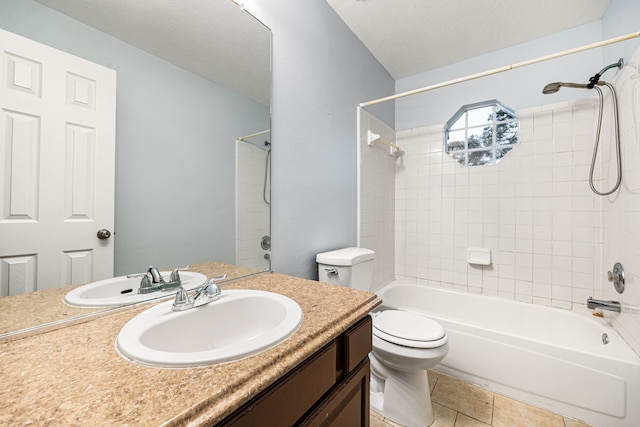 full bathroom featuring vanity, tile patterned floors, tiled shower / bath combo, toilet, and a textured ceiling