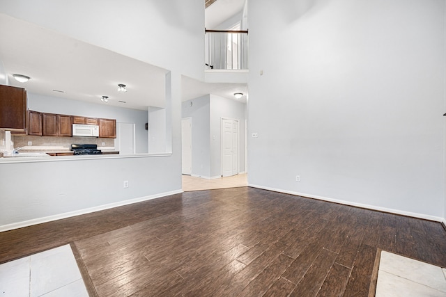 unfurnished living room featuring light hardwood / wood-style floors, a towering ceiling, and sink