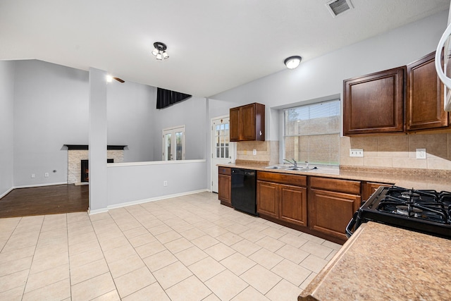 kitchen featuring black appliances, a stone fireplace, sink, decorative backsplash, and light tile patterned floors