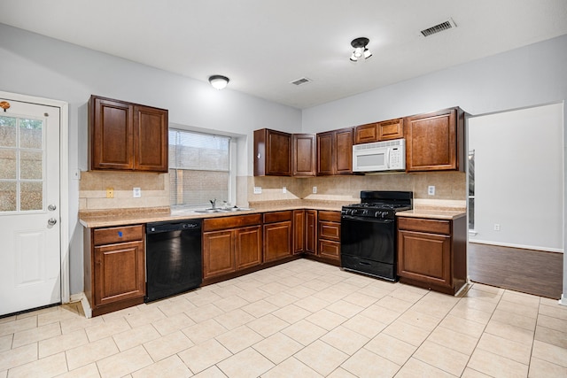 kitchen with tasteful backsplash, sink, light tile patterned floors, and black appliances