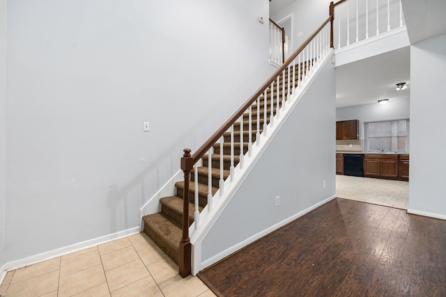 stairway featuring a towering ceiling, tile patterned floors, and sink