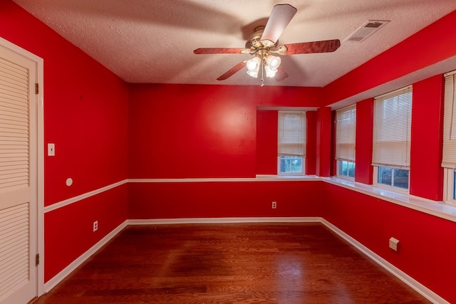 empty room featuring ceiling fan, a textured ceiling, and dark hardwood / wood-style flooring