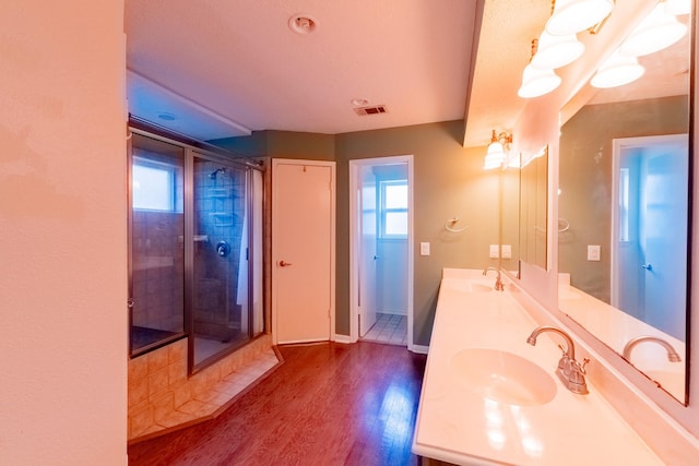 full bath featuring double vanity, a sink, a stall shower, and wood finished floors