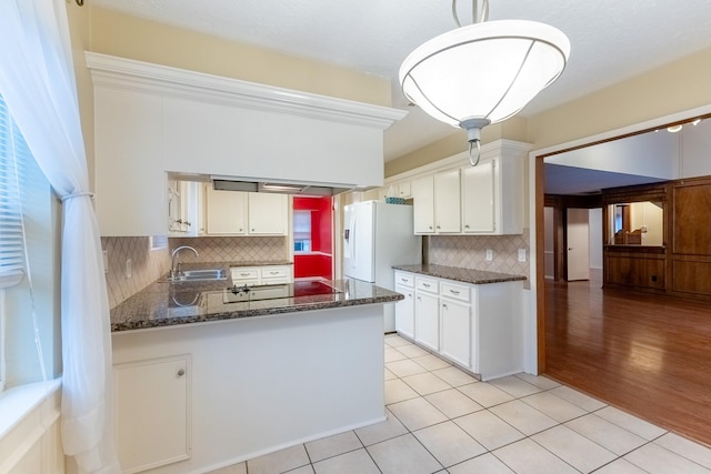 kitchen with tasteful backsplash, white cabinets, white refrigerator with ice dispenser, kitchen peninsula, and black electric cooktop