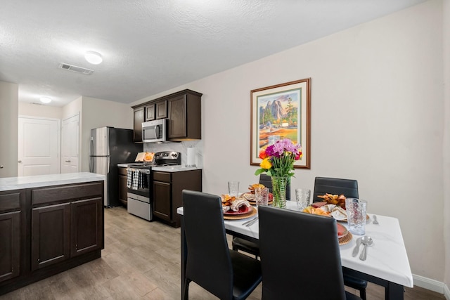 dining space with light hardwood / wood-style floors and a textured ceiling