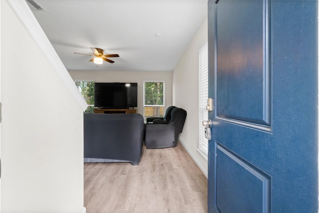 living room with light hardwood / wood-style floors, ceiling fan, and crown molding