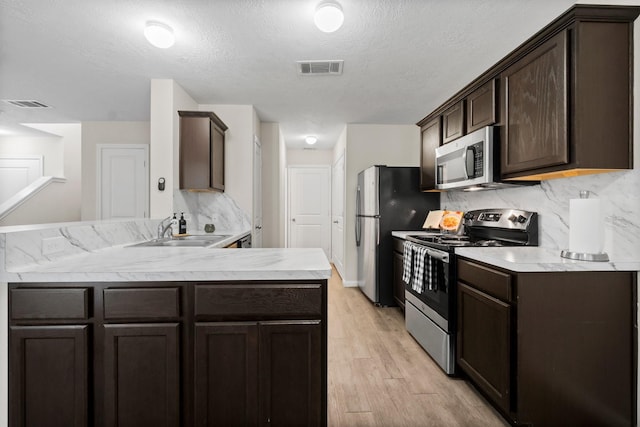 kitchen featuring sink, stainless steel appliances, dark brown cabinets, and light hardwood / wood-style floors