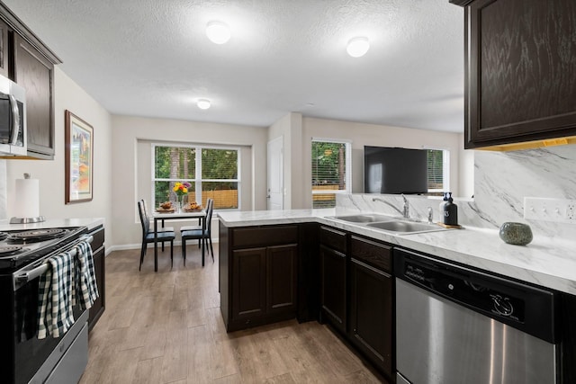 kitchen featuring kitchen peninsula, appliances with stainless steel finishes, dark brown cabinetry, sink, and light hardwood / wood-style flooring