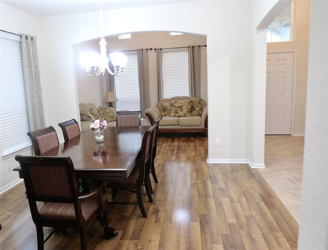 dining area with light wood-type flooring and an inviting chandelier